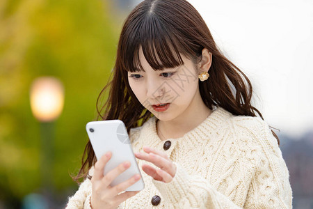 亚洲日语年轻女经营智能手机图片