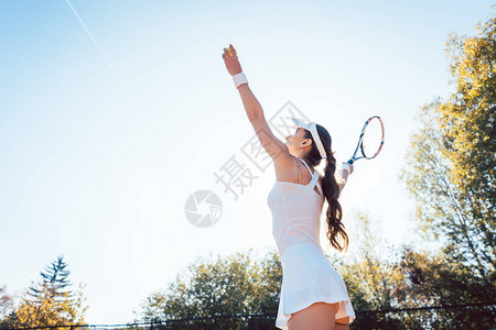女子在球场上的网球比赛中发球图片