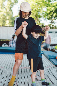 大哥教小弟跳蹦床孩子们手牵积极休闲蹦床运动周末在杂技和蹦床运图片