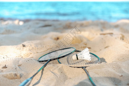 近距离观看躺在沙滩上的羽毛球拍和羽毛球图片