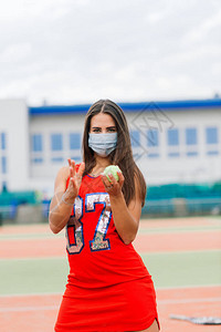 网球运动员女孩戴着防护面具在外面拿着球的肖像图片