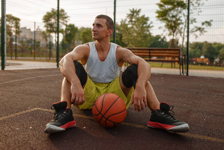 篮球运动员坐在室外球场的地上街球训练后穿着运动服的图片