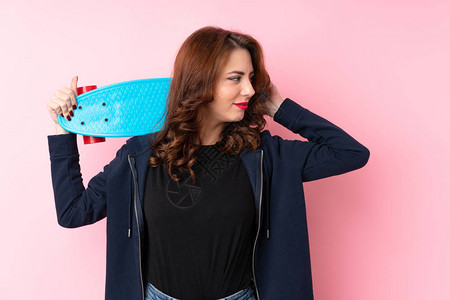 俄罗斯年轻女身穿孤立的粉红背景穿着滑冰和仰视背景图片