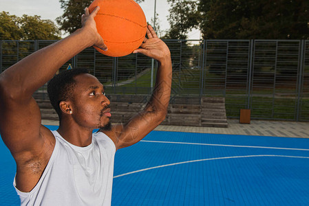 年轻的黑人非洲裔美国篮球员在篮球场上穿着白色t恤的肖像图片