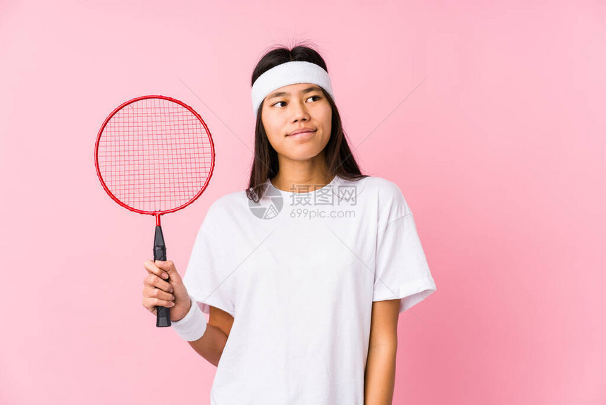 年轻女人在粉红背景下打羽毛球图片