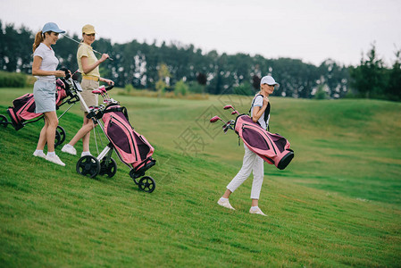 穿着马球和帽子的女在高尔夫球场的绿色草坪上图片