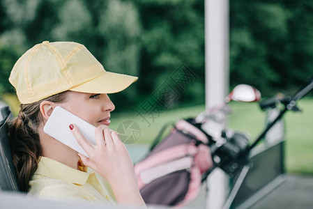 在高尔夫球场用智能手机说话的女高尔图片