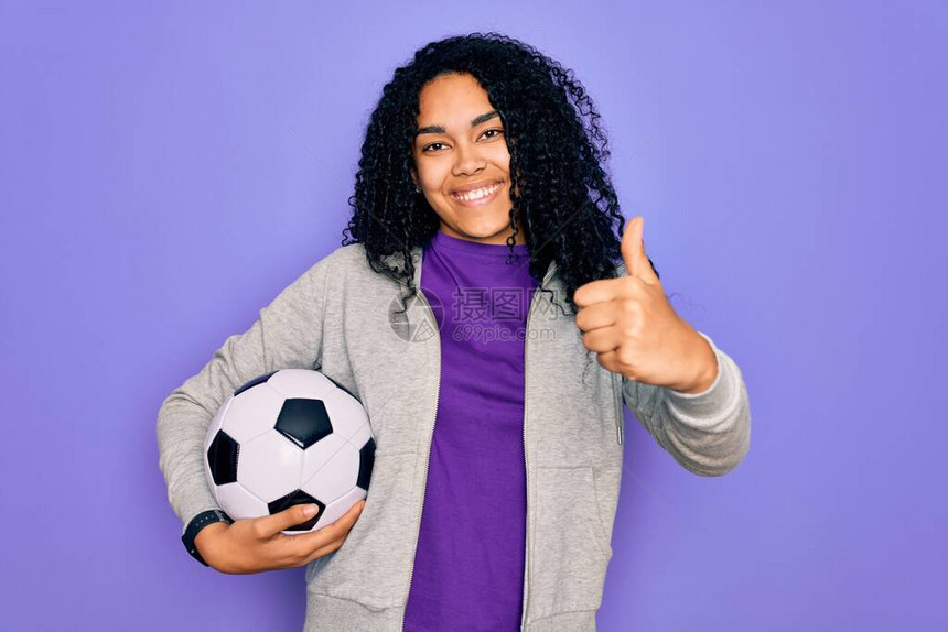 非洲裔美国卷发女球员在紫色背景下踢足球图片