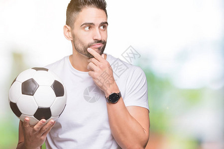 年轻男子在孤立的背景中带着足球面对着严肃的反感思考问题图片