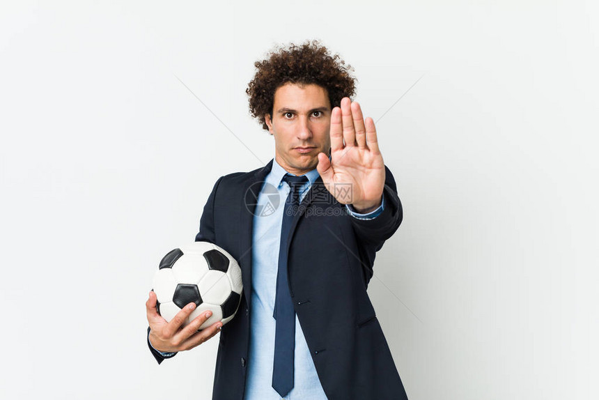 足球教练拿着球站着伸展的手举着停牌图片