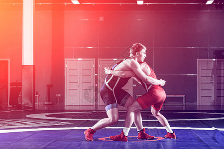 两名身穿蓝色和红色摔跤紧身衣的强壮摔跤手正在摔跤图片