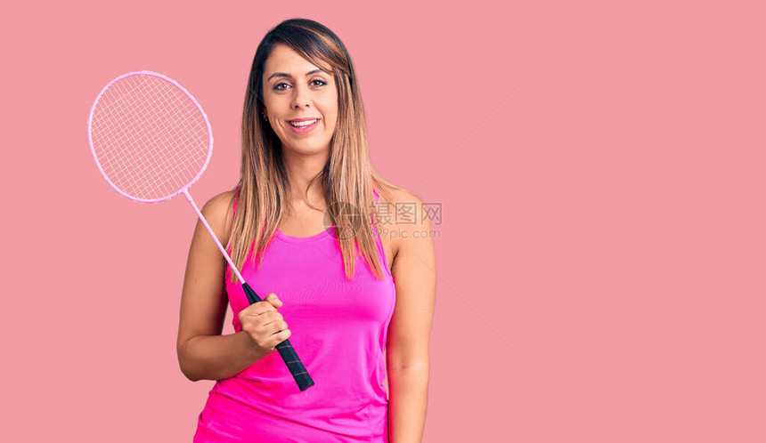 年轻美女拿着羽毛球拍子看着正面和快乐的站立笑着满怀自信的微图片