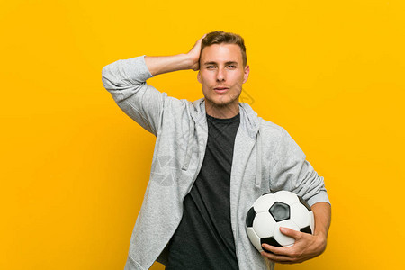 年轻caucasian男子拿着足球被震惊图片