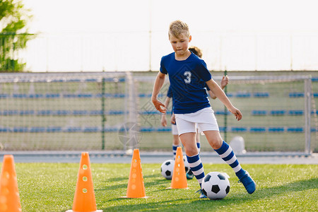 足球训练营展板孩子们的足球训练营男孩们在田野里练习运球员发展良好的足球运技巧孩子们用球和锥体训练足球激流回旋训练以提高背景