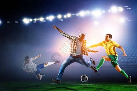身着散衣的黑人与两名专业足球运动员在夜空运动场上玩足球图片