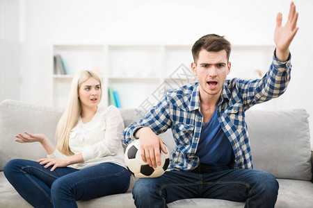 愤怒的男子看着足球在沙发上靠图片