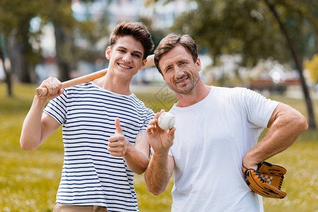 带着软球棒的少年男孩在父亲身边露出拇指图片