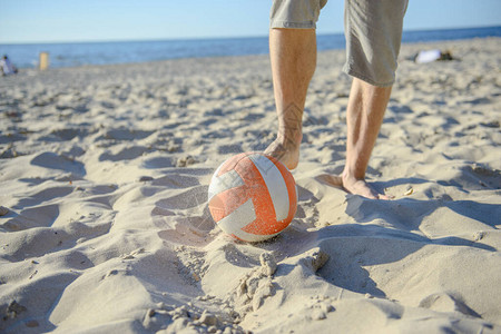 男子在海滩上踢足球图片