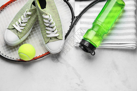 网球拍鞋子毛巾水瓶和浅色背景中的球图片