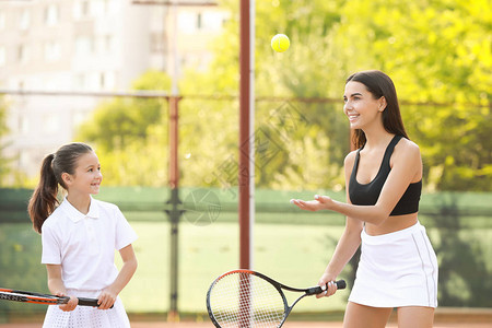 小女孩和她妈在球场上打网球图片