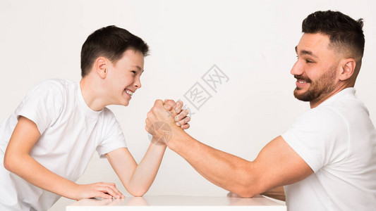 玩耍的爸和儿子在手臂摔跤比赛轻拍图片