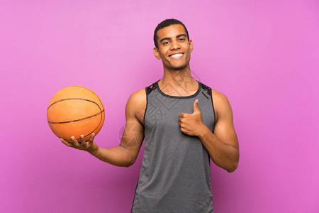 年轻运动员在孤立的紫色墙壁上打篮球图片