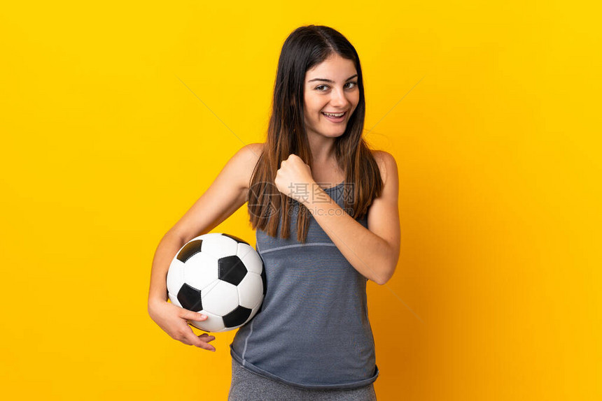 年轻女足球运动员在黄色背景下被孤立的女图片