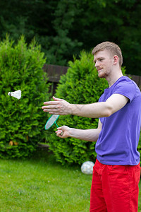 白种人以绿色背景玩羽毛球和穿梭孔雀在草地上玩羽毛球的业余游戏户图片