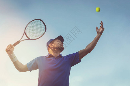 活跃的年轻人在户外打网球在蓝天下发球图片