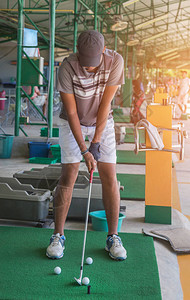 有金属高尔夫球杆的高尔夫球手准备在高尔夫球场院子标志的练习图片