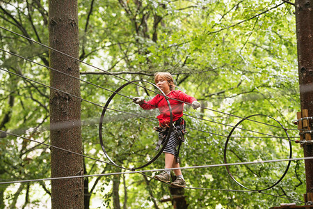 森林探险公园中小男孩高在绳上行走图片