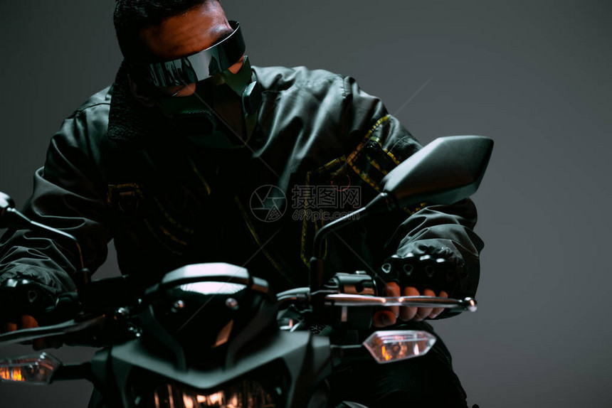戴面具的双种族赛博朋克玩家和骑着灰色摩托车的未来派眼镜图片