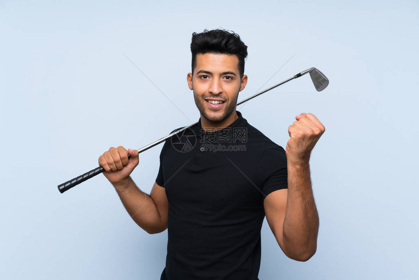 英俊的年轻人打高尔夫在孤立的蓝背景下打高尔图片