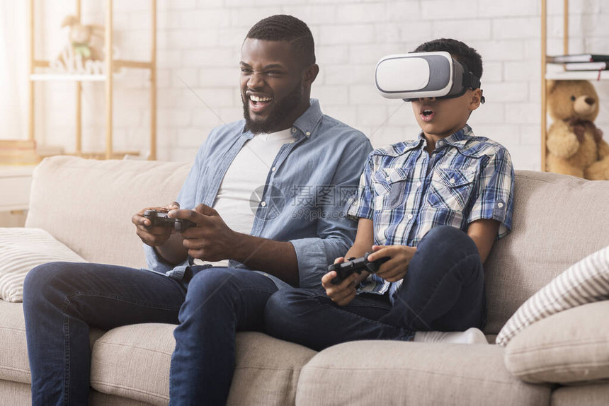 美国非裔父亲和儿子在家中尝试VR眼镜图片