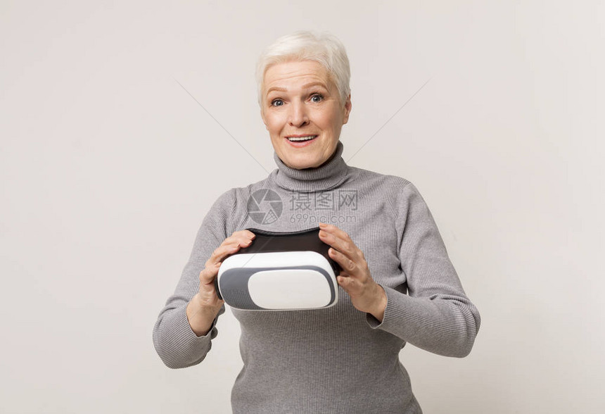 现代技术和老年老妇人在使用VR耳机后对体验虚拟现实感到惊讶图片