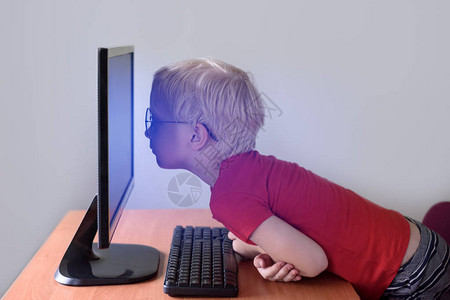 戴眼镜的金发男孩将鼻子埋在监视器里互联网图片