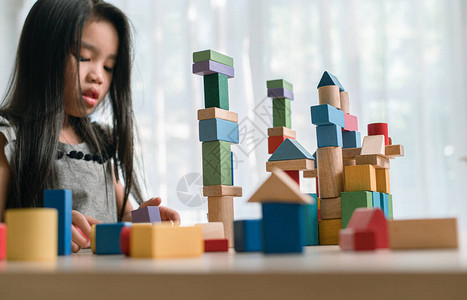 快乐的小女孩从五彩的木块玩游戏建筑构造塔学习和图片