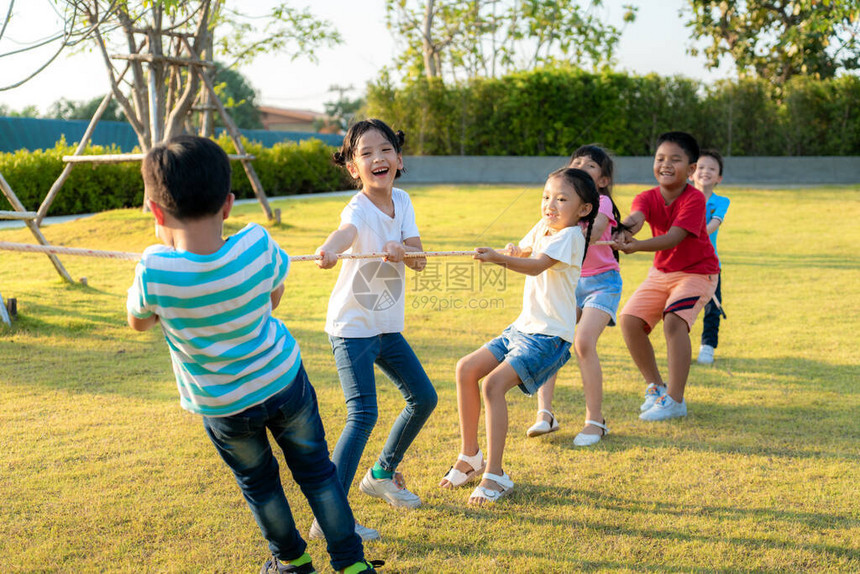 一群快乐的亚裔儿童在夏季天到城区公园操场玩拖战或拉绳牵引器图片