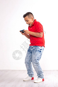 一个穿着红色衬衫和牛仔裤的小男孩站着电话图片