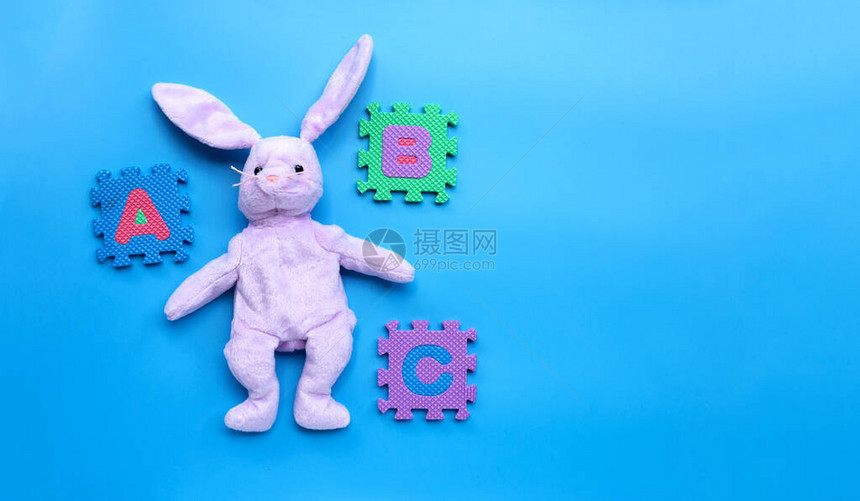 蓝背景上的兔子用英语字母拼图玩耍教育概念图片
