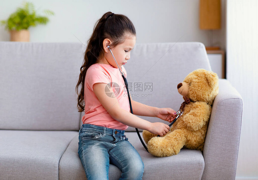 可爱的女婴和泰迪熊医生在家用立体镜治疗玩具在图片