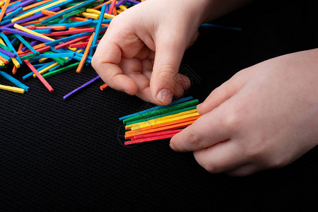 小孩用彩色木棍在白色背景上发挥创造力图片