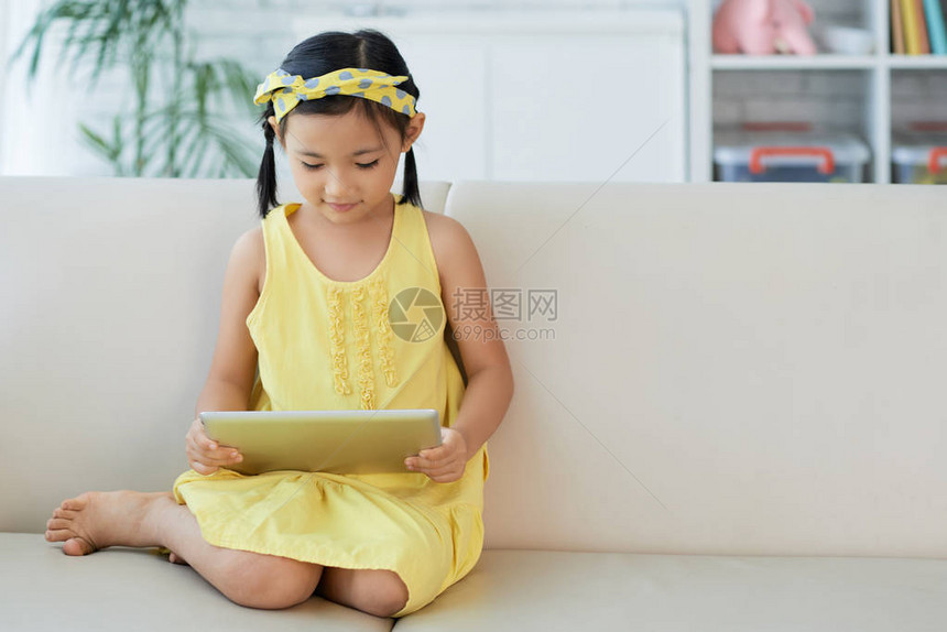 穿亮黄色礼服在平板电脑上玩游戏图片