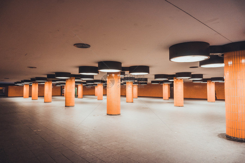 带圆形天花板灯棕色柱子和灰色地板的空荡的现代宽敞会议厅的图片