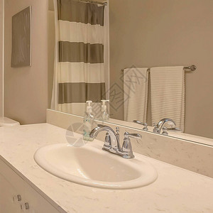 广场浴缸和在小浴室内用带条纹的窗帘淋浴图片
