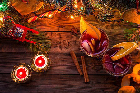 两杯含橙色切片的面包红酒蜡烛和圣诞树图片