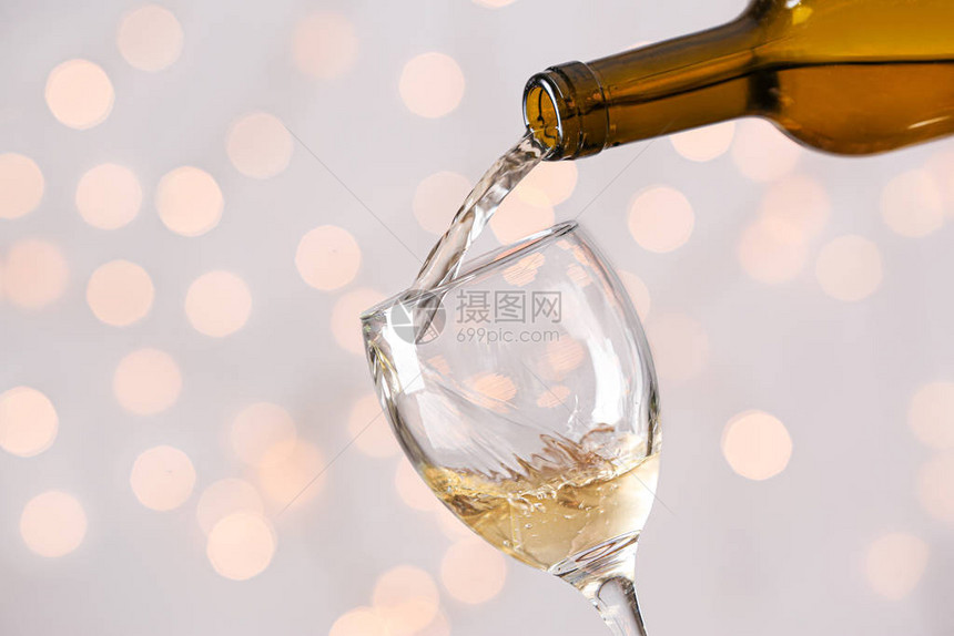在浅色背景下将酒从瓶中倒入玻璃杯中图片