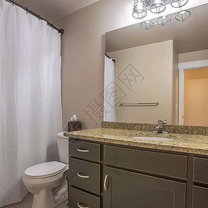 方形梳妆台马桶和毛巾钩靠在光线充足的浴室的白墙上浴缸和淋浴间隐藏在图片