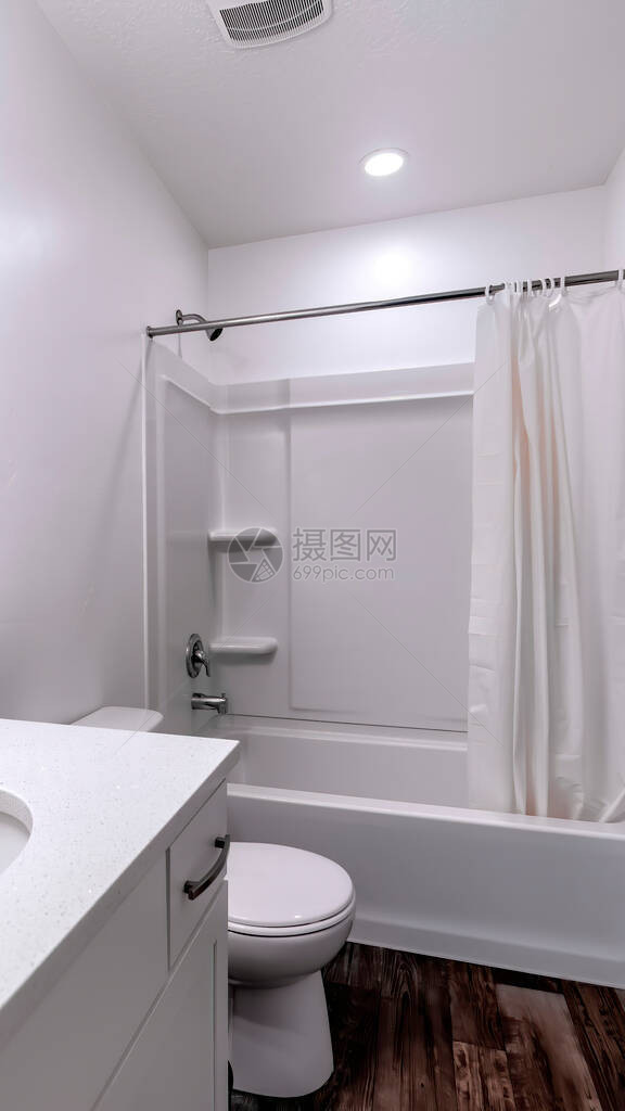 垂直清洁白色浴室内部配有椭圆形水槽镜马桶浴缸和淋浴房间内还可以看到灰色的毛巾金属棒图片