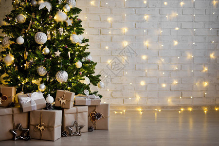 圣诞树和成堆的礼品箱用黄灯在白砖背景图片